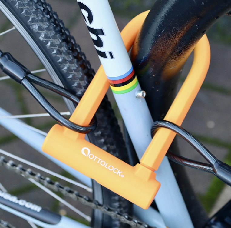 OttoLock SIDEKICK Security Cable and orange SIDEKICK U-Lock securing a bike frame and wheel together